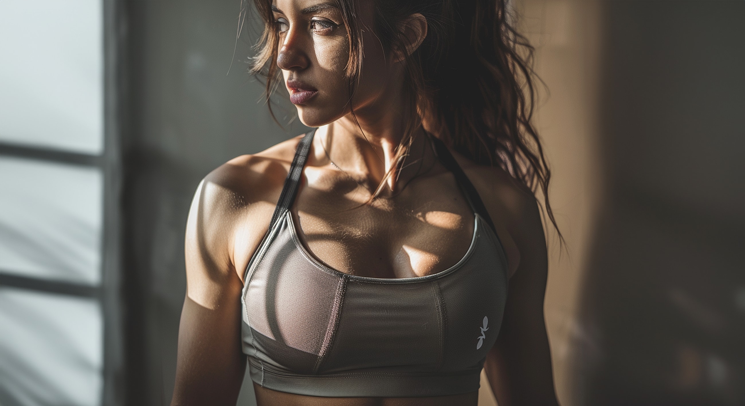 Athletic woman in sports bra and sunlight shadows.